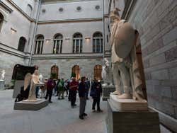 People walking around a courtyard with sculptures
