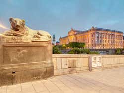 A statue of a lion on a plinth with the Royal Palace behind