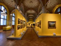 A room of art on yellow walls in a museum